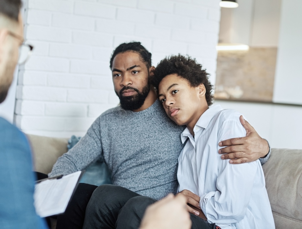 Father hugging his teen son for parental therapy support session