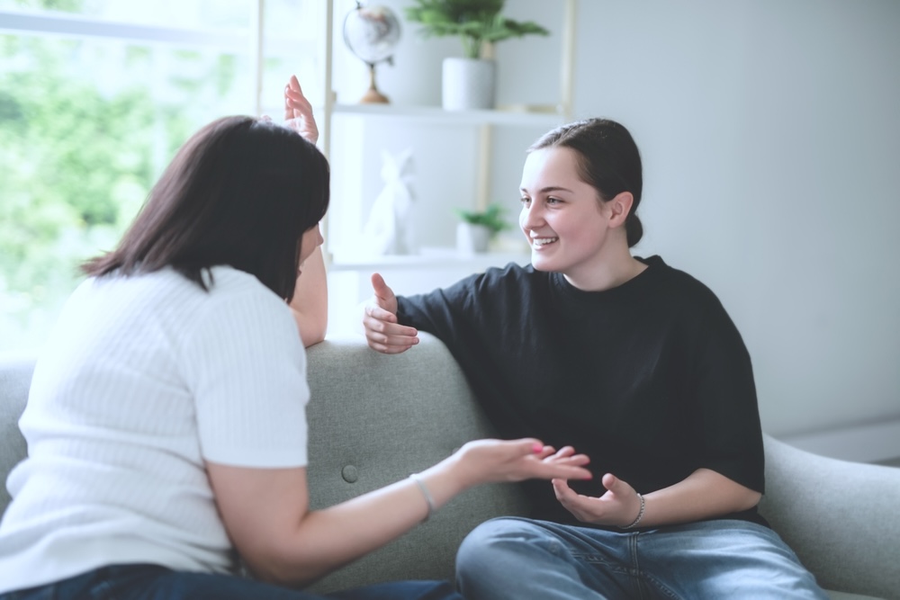 Teen and parent smiling together in their home